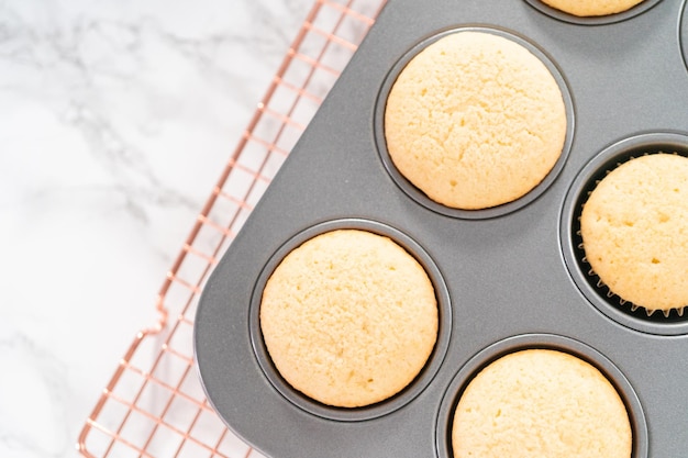 Frisch gebackene Vanille-Cupcakes auf einem Trockengestell abkühlen.