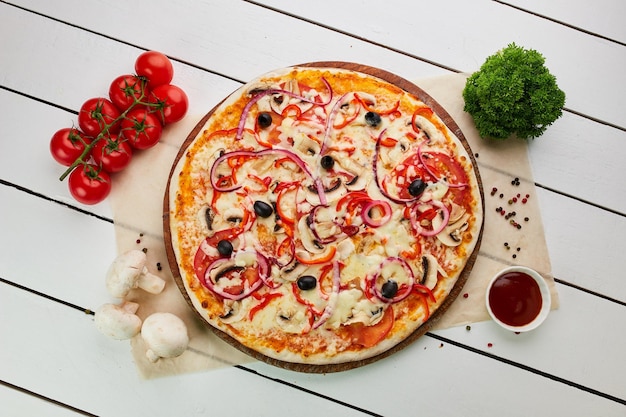 Frisch gebackene vegetarische Pizza mit Tomaten, Pilzen, Paprika, Oliven, Zwiebeln und Mozzarella, serviert auf Holzhintergrund mit Saucen und Kräutern Food-Delivery-Konzept Restaurantmenü