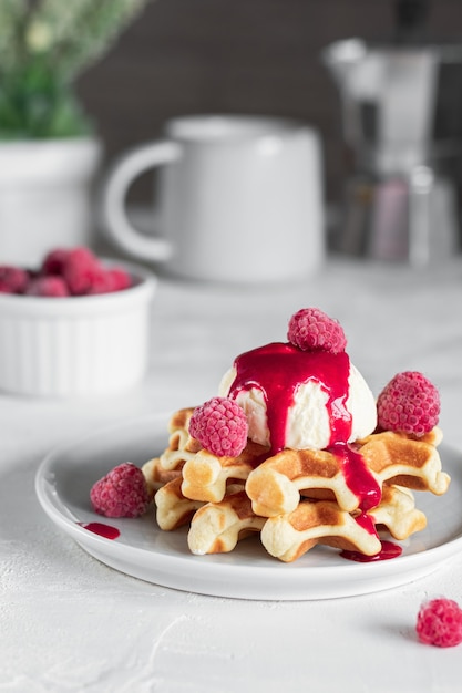 Frisch gebackene Waffeln mit Himbeersirup und Eis auf einem Teller