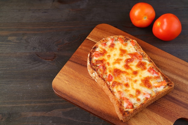 Frisch gebackener hausgemachter Pizzatoast mit zwei frischen Tomaten auf Holztisch