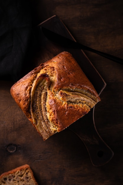 Frisch gebackenes Bananenbrot auf einem Holzbrett schneiden