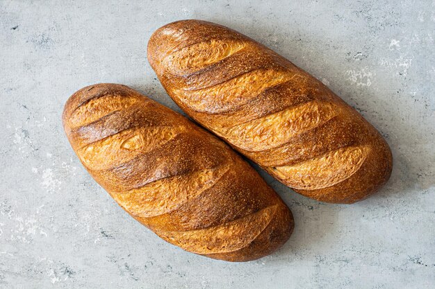 Frisch gebackenes Brot auf einem Holzbrett auf hellgrauem (blauem) Hintergrund. Traditionelles frisches Brot