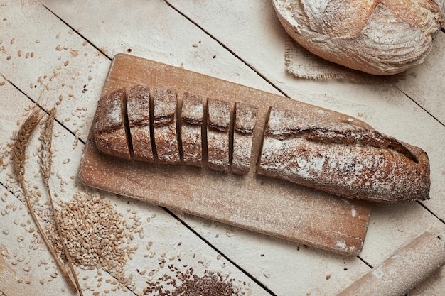 Frisch gebackenes Brot Draufsicht auf geschnittenes Vollkornbrot auf dunklem, rustikalem Holzhintergrund, Nahaufnahme