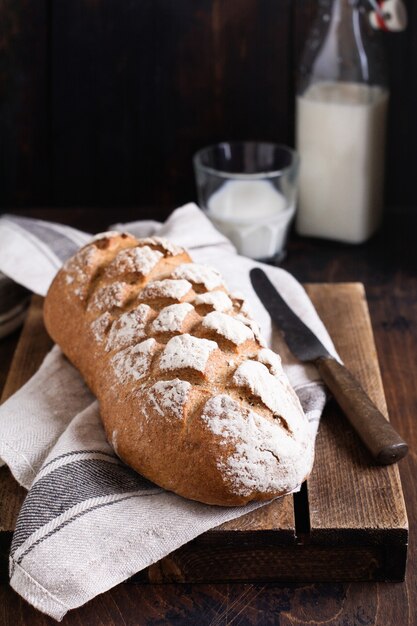 Frisch gebackenes hausgemachtes Brot mit Milch auf einem alten Holztisch. Rustikaler Stil.