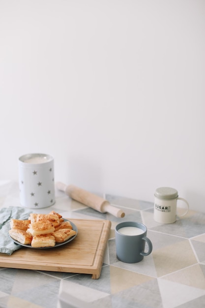 Frisch gebackenes hausgemachtes Gebäck am Küchentisch Frühstück mit Blätterteigbrötchen und einem Glas Milch