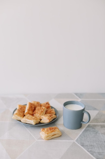 Frisch gebackenes hausgemachtes Gebäck am Küchentischfrühstück mit Blätterteigbrötchen und einem Glas Milch