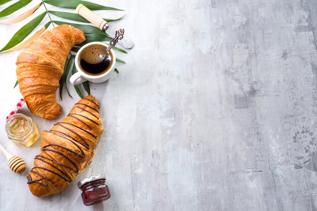 Frisch gebackenes Hörnchen und Tasse Kaffee verziert mit Schokoladensoße