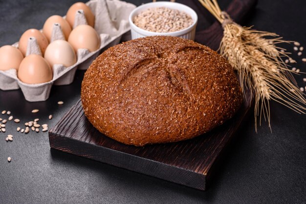 Frisch gebackenes Schwarzbrot mit Ähren und Weizenkörnern