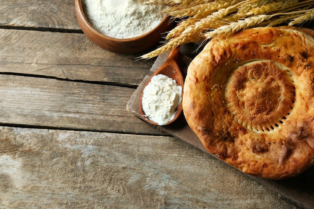 Frisch gebratenes Brot mit Weizenmehl auf Holzhintergrund