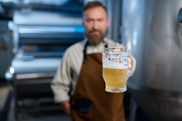 Foto frisch gebrautes craft beer in brauereiarbeiterhand, selektiver fokus