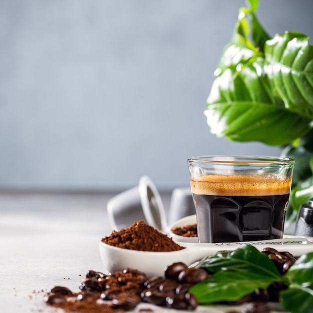 Frisch gebrühter Kaffee in einer Glasschale mit Bohnen und Blättern. Oberfläche für Lebensmittelgetränke mit Platz für Kopien