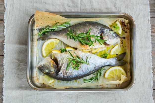 Frisch gegrillter gerösteter Dorado-Dorada-Fisch aus dem Meer mit Zitronen-Rosmarin-Oregano-Kräutern-Olivenöl auf dem Küchentisch Draufsicht flach liegender Hintergrund