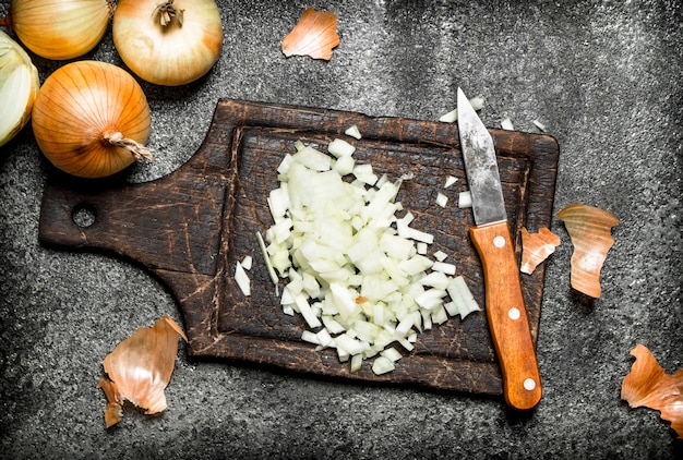 Frisch gehackte Zwiebel auf dem alten Brett. Auf rustikalem Tisch.