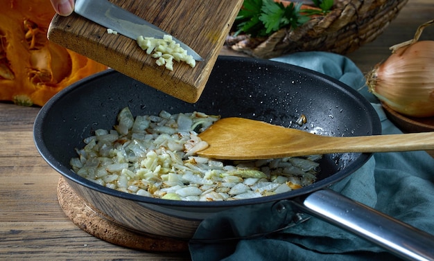 Frisch gehackter Knoblauch wird zu gebratenen Zwiebeln hinzugefügt