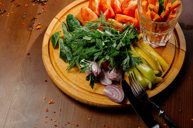 Frisch gehacktes Gemüse auf einem Holzbrett. Vorspeise von frischen Tomaten, Gurken, Radieschen und Kräutern. Draufsicht. Das Konzept der gesunden Ernährung, Ernährung, Vegetarismus.