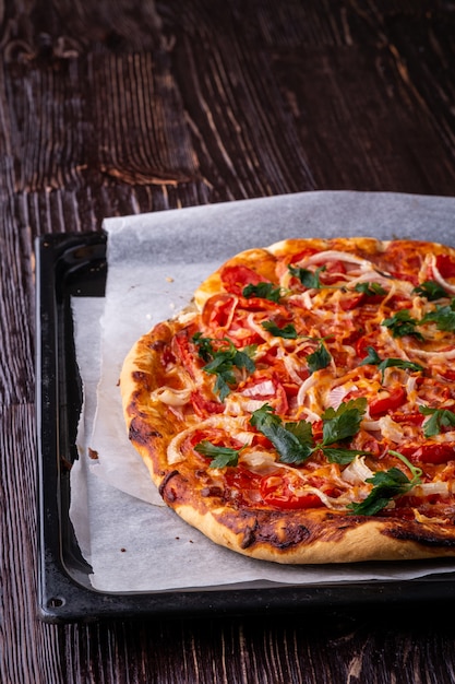 Frisch gekochte heiße Pizza und Scheiben mit Käse Schinken Fleisch Tomaten Zwiebel Petersilie hausgemacht