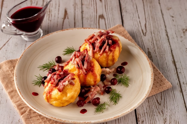 Frisch gekochte schwedische Kartoffelknödel mit Preiselbeersauce auf hellem Hintergrund.