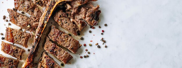 Frisch gekochtes saftiges Tbone-Steak mit Rosmarin- und Knoblauchgewürzen auf hellem Marmorhintergrund