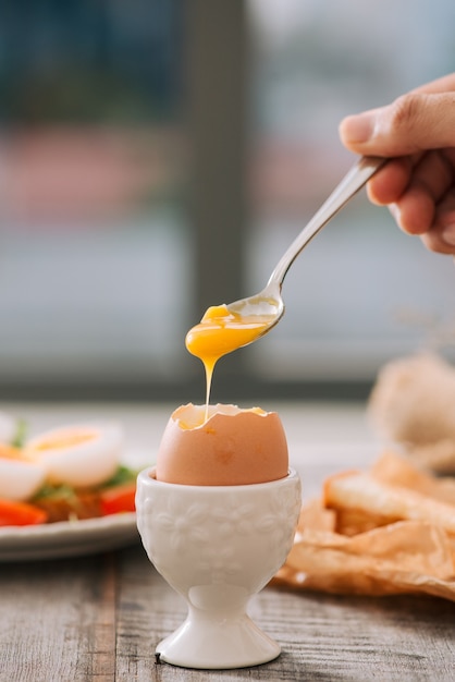 Frisch gekochtes weißes Ei auf Holzbrett. Gesundes Fitness-Frühstück.