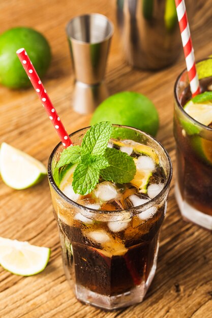 Frisch gemachtes Cuba Libre mit braunem Rum, Cola, Minze und Zitrone auf Holztisch