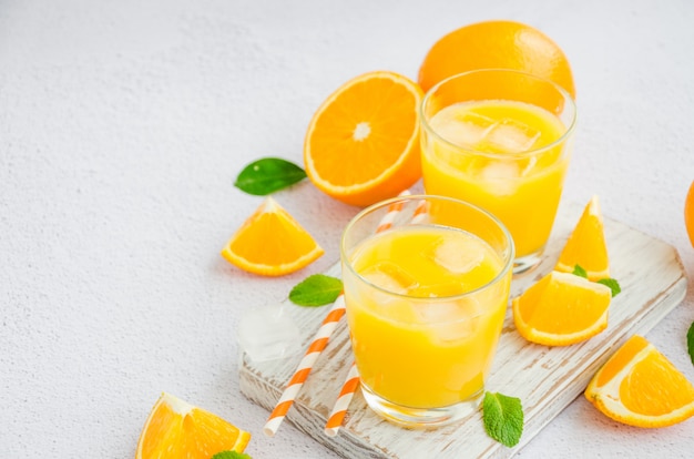Frisch gepresster Orangensaft mit Eis in einem Glas und Strohhalmen