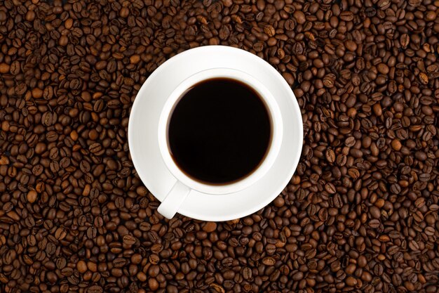 Frisch gerösteter Kaffeebohnenhintergrund mit einer weißen Tasse heißem Filterkaffee-Espresso-Banner Flat Lay Draufsicht Hintergrund Kaffeebohnen