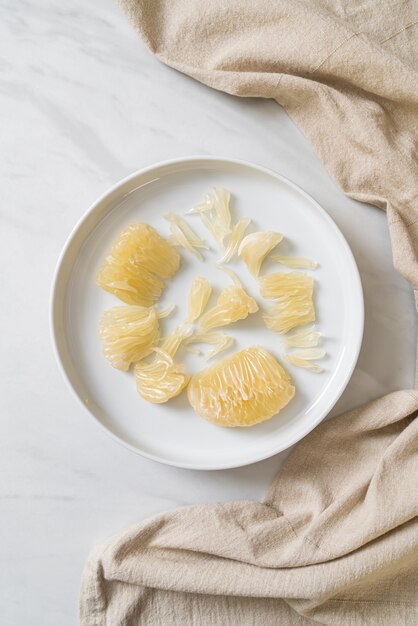 Frisch geschälte Pampelmuse, Grapefruit oder Schellfisch auf weißem Teller