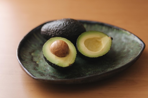 Frisch geschnittene Avocado auf grünem Teller Vegetarisches Essenskonzept