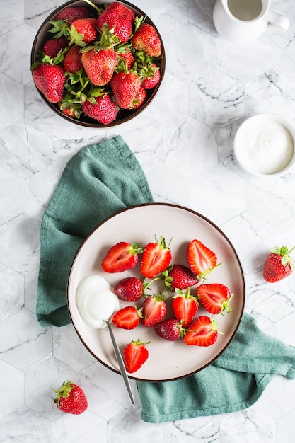 Frisch geschnittene Erdbeeren und Joghurt auf einem Teller Gesundes Vitamin-Dessert Ansicht von oben und vertikal