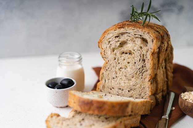 Frisch geschnittenes, hausgemachtes Vollkornweizenbrot mit Olivenöl auf weißem, rustikalem Hintergrund