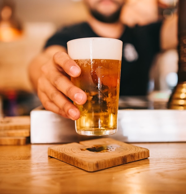 Frisch gezapftes Bier. Barkeeper hält ein frisch gezapftes Glas Bier in der Hand