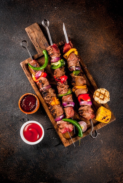 Frisch, hausgemacht auf dem Grill Feuer Fleisch Rindfleisch Schaschlik mit Gemüse und Gewürzen, mit Barbecue-Sauce und Ketchup,