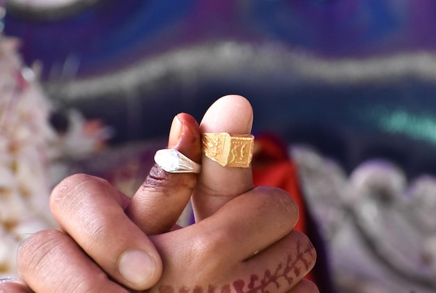 Frisch verheiratete indische Paare halten sich an der Hand und zeigen ihre Ringe