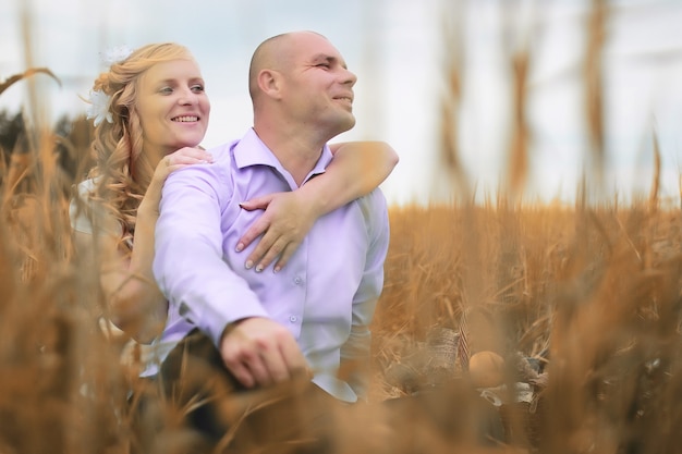 Frisch verheiratete Liebhaber, die am Herbsttag auf einem Feld spazieren gehen