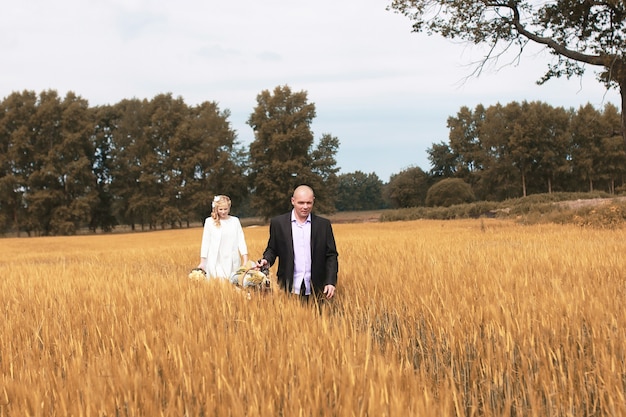 Frisch verheiratete Liebhaber, die am Herbsttag auf einem Feld spazieren gehen