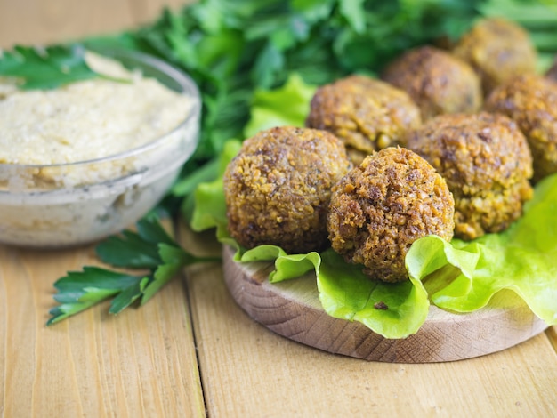 Foto frisch zubereitete falafel auf einem schneidebrett mit sauce tahina und petersilie und dill