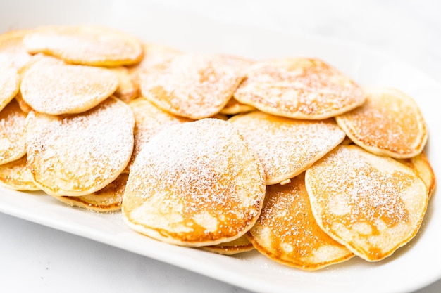 Frisch zubereitete kleine Pfannkuchen auf Kefir-Basis, garniert mit Puderzucker.