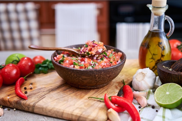 Frisch zubereitete salsa-dip-sauce, gehackte knoblauchtomaten und zwiebeln in holzschüssel