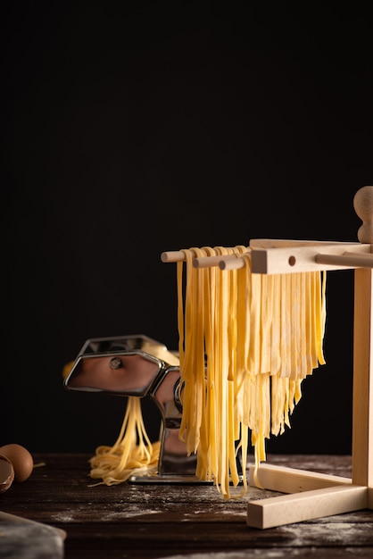 Frisch zubereitete Tagliatelle Paste wird auf einem hölzernen Trockner, traditionelle italienische Küche getrocknet