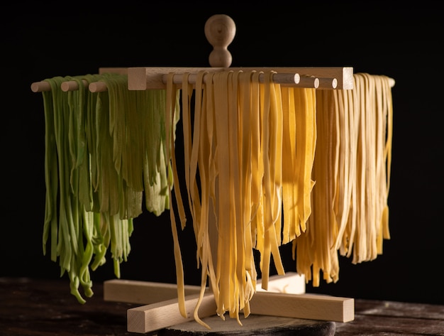 Frisch zubereitete Tagliatelle Paste wird auf einem hölzernen Trockner, traditionelle italienische Küche getrocknet