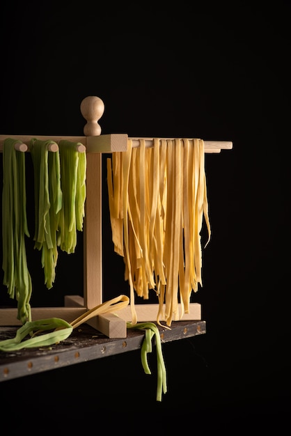 Frisch zubereitete Tagliatelle Paste wird auf einem hölzernen Trockner, traditionelle italienische Küche getrocknet