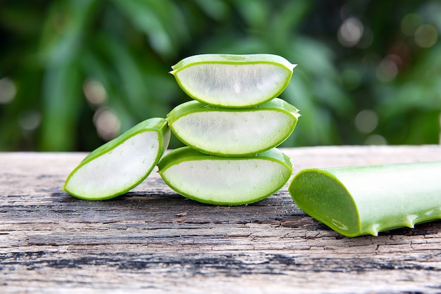 Frische Aloe Vera-Blätter und -scheiben auf Holztisch