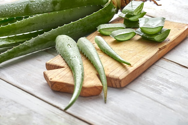 Frische Aloe-Vera-Blätter und -Scheiben mit Wassertropfen auf Holzhintergrund. naturheilkundliches konzept