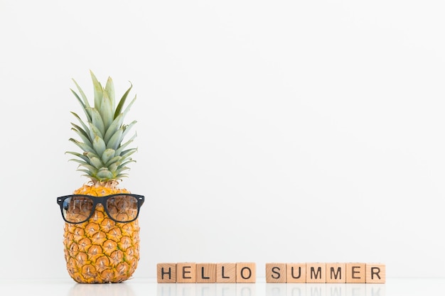 Frische Ananas mit Sonnenbrille auf farbigem Hintergrund Hallo Sommer