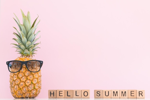 Foto frische ananas mit sonnenbrille auf farbigem hintergrund hallo sommer