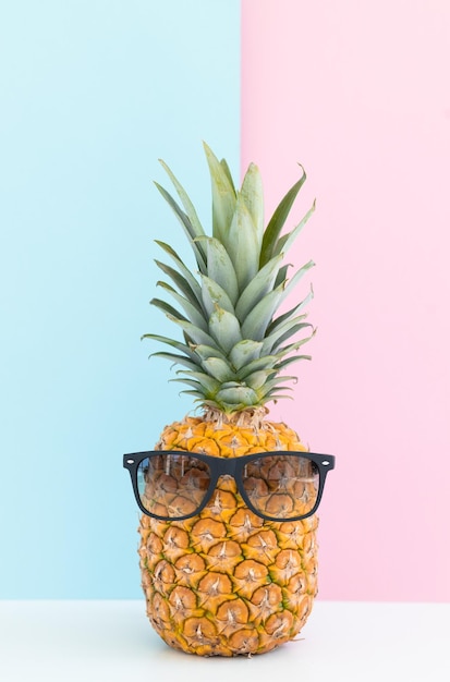 Frische Ananas mit Sonnenbrille auf farbigem Hintergrund