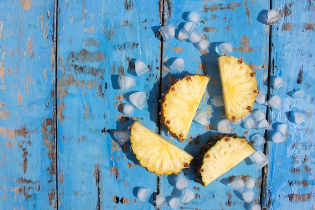 frische Ananas und Eiswürfel auf blauem Holzhintergrund