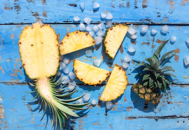 frische Ananas und Eiswürfel auf blauem Holzhintergrund