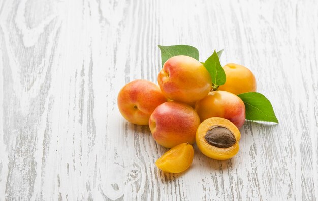 Frische Aprikosen mit Blättern auf weißem Holzhintergrund Gesunde und umweltfreundliche Früchte auf dem Bauernhof Rustikaler Stil