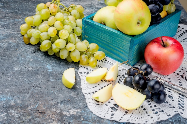 Frische ausgewählte Äpfel und Trauben und Fruchtpastille auf dunklem Hintergrund